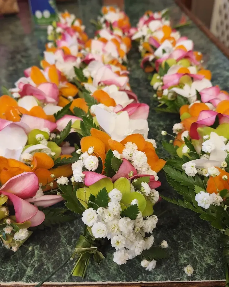 A table of fresh orange and coral leis ready for an event